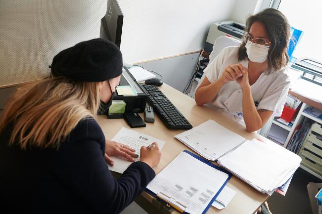 Une soignante fait signer des papier à sa patiente